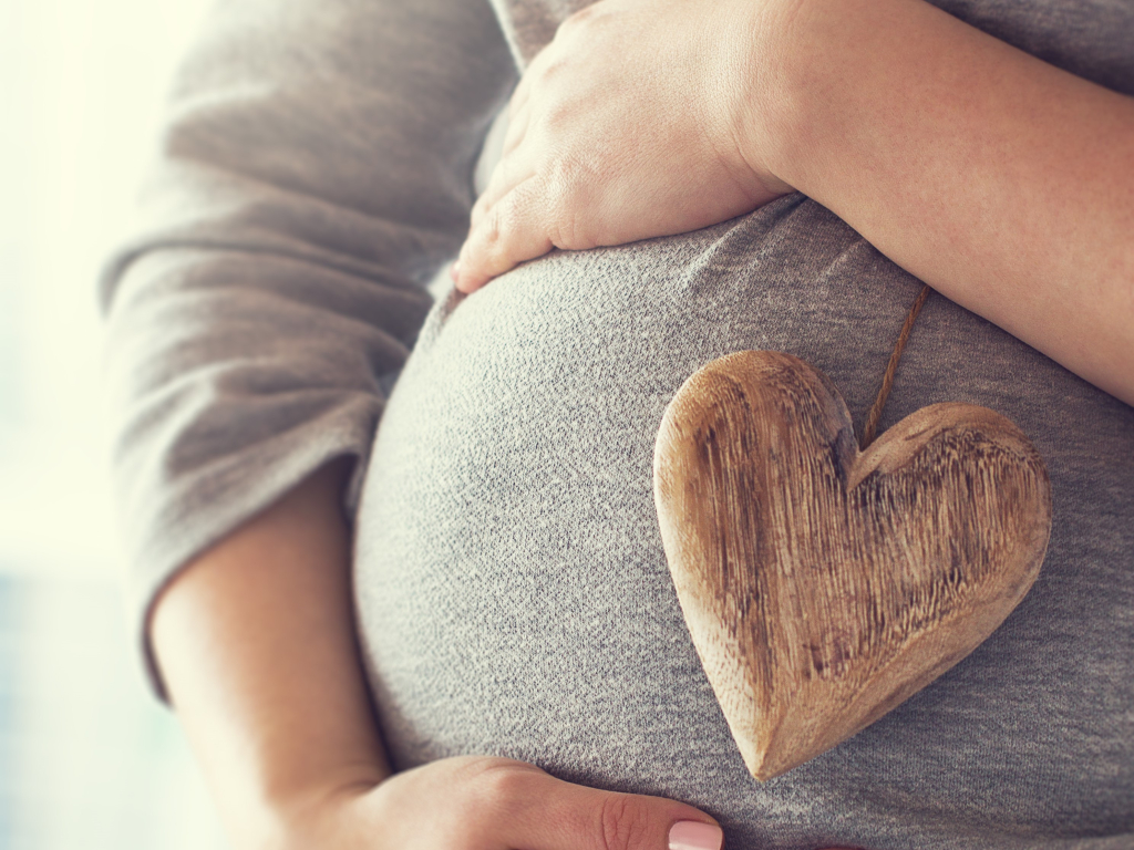 pregnant-woman-holding-heart-while-touching-her-belly.jpg